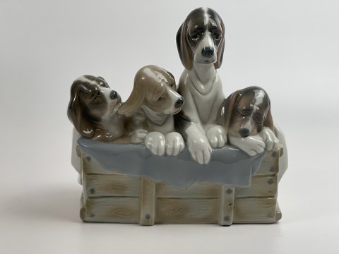 Lladro figure with dogs, probably by Juan Huerta, 4 puppies with blanket; 
sitting on a "wooden box", 20th century