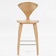Cherner Bar Stool i hvidolieret egetræ.
I dag betragtes Cherner-stolen som et moderne ikon indenfor møbeldesign. Stolen 
blev tegnet i 1958 af den indflydelsesrige amerikanske arkitekt Norman Cherner. 
Den opnåede kendis-status i hjemlandet, da hans navnebror, den folkekære 
kunstmaler Norman Rockwell, tre år senere afbildede den i maleriet, The Artist 
at Work.
Stolen fås i flere varianter. Kon