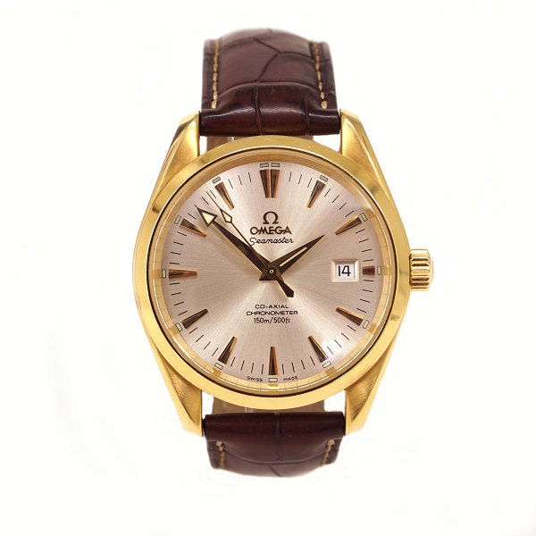 Omega Seamaster Aqua Terra Co-Axial Escapement i 18kt guld. Ref. 26033037. 
Kaliber 2500. Leveres med boks og certifikater. Årgang 2008. D: 39mm. Leveres på 
original Omega læderrem med foldespænde i 18kt guld. Rem dog med brugsspor